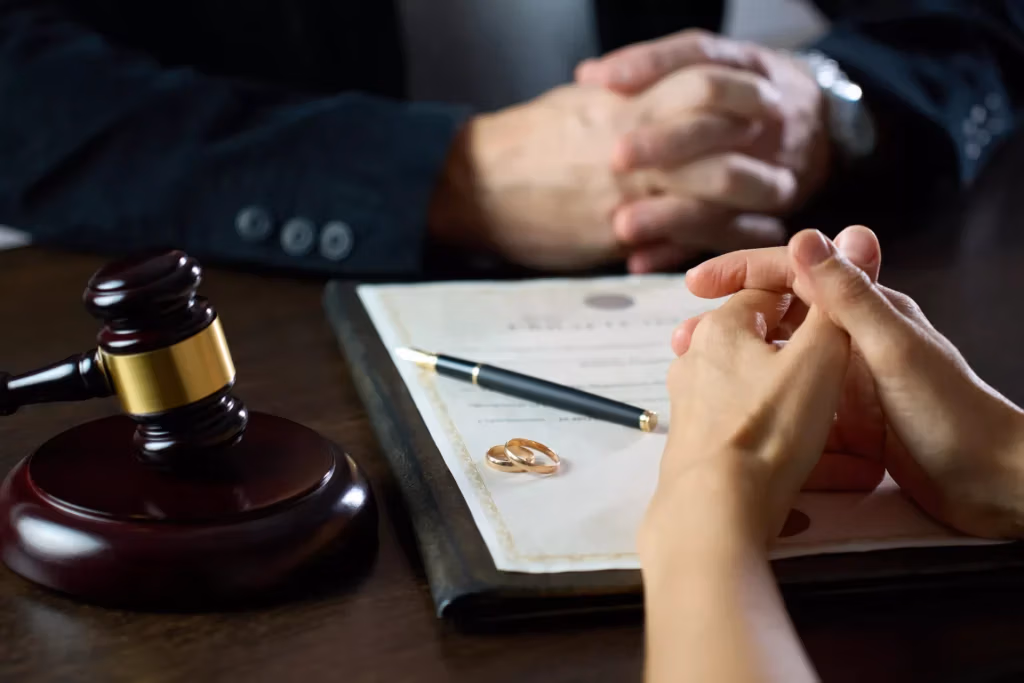 two people look over a divorce agreement with wedding rings placed on top of it