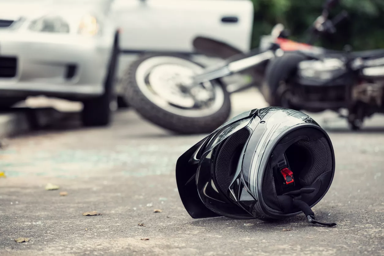 close-up of a helmet of a driver with a blurred motorbike and car in the background
